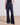 Navy blue flared pants worn by a person on a beige floor with a light gray wall background