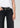 Person wearing black jeans with a belt on a plain background
