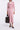 Person wearing a pink outfit with a black handbag on a white background