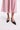 Person wearing a pink skirt and black shoes on a white background