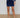 Person wearing a navy blue outfit with white buttons on a wooden floor.