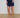 Navy blue skirt with white trim worn by a person on a wooden floor.