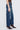 Person wearing blue jeans and brown shoes on a white background