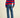 Person wearing a red and blue striped sweater with blue jeans on a beige background