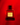Red perfume bottle with gold label on a red background